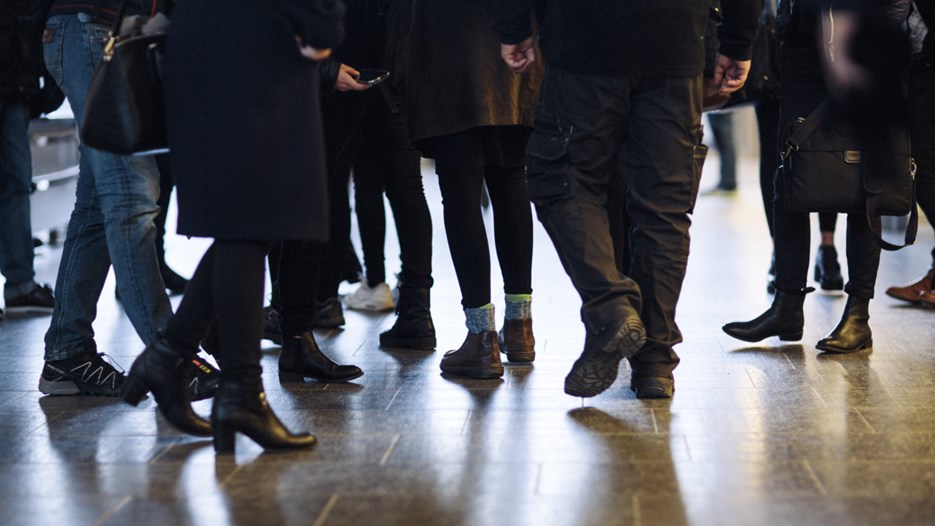 picture of several students legs and feet walking across a campus corridor