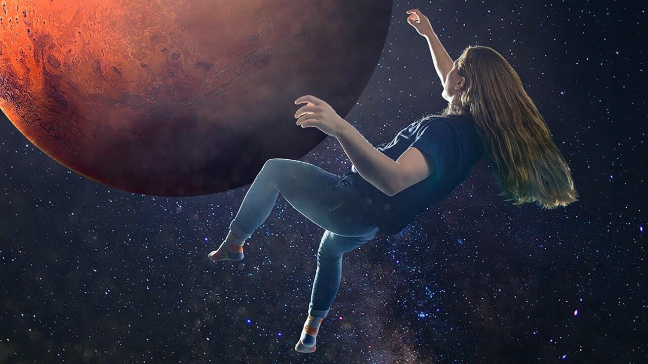 En ung kvinna svävar i rymden framför ett rött klot