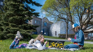 Two children  on the lawn, in front of Curiosum`s  dome theater. Between them, a basket dressed with dandelions.