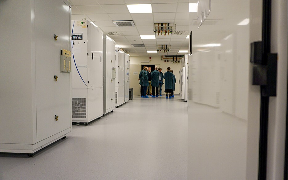 Korridor med vita odlingsskåp på båda sidor och en grupp av människor i gröna labbrock i slutet av korridoren