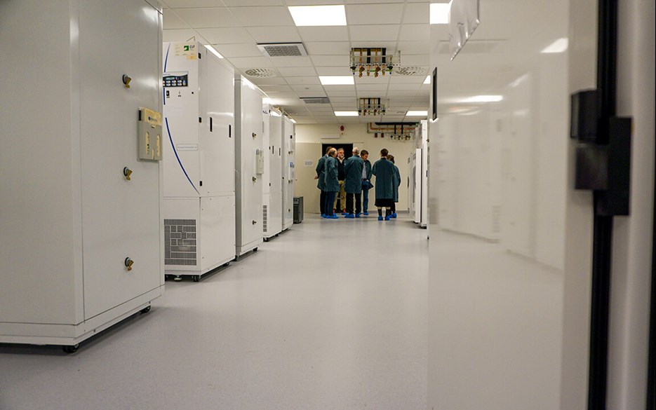 Korridor med vita odlingsskåp på båda sidor och en grupp av människor i gröna labbrock i slutet av korridoren
