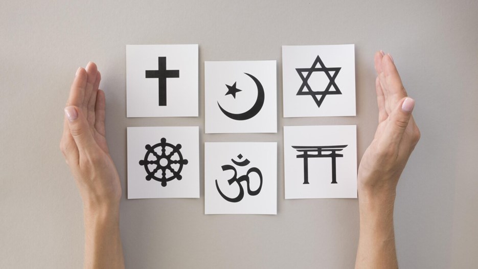 Olika religiösa symboler mellan ett par händer