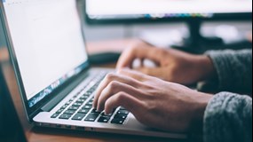 Two hands writing on a laptop