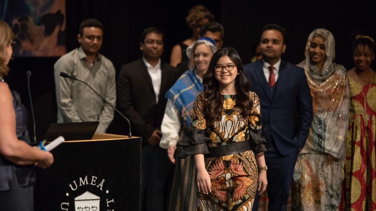 Graduating student Nora Nindi Arista receives a congratulatory scroll on stage at the ceremony 2018 scenen