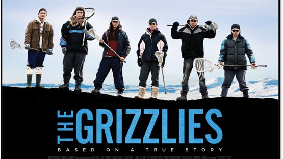 The actors from the film are lined up with lacrosse equipment in front of a light blue sky