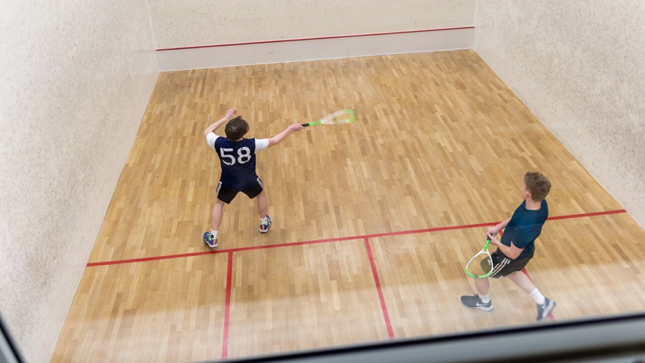 Två killar spelar squash.