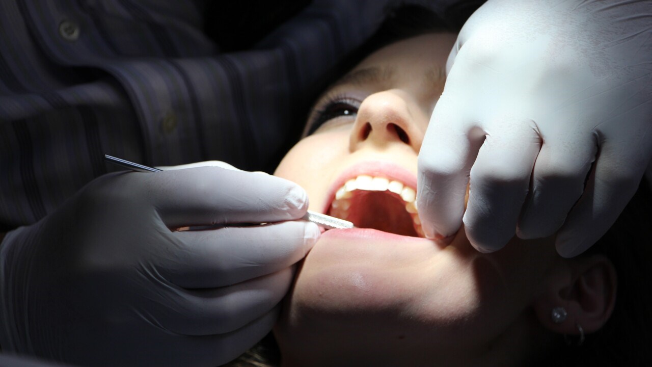 Person som får sina tänker undersökta av en tandläkare.