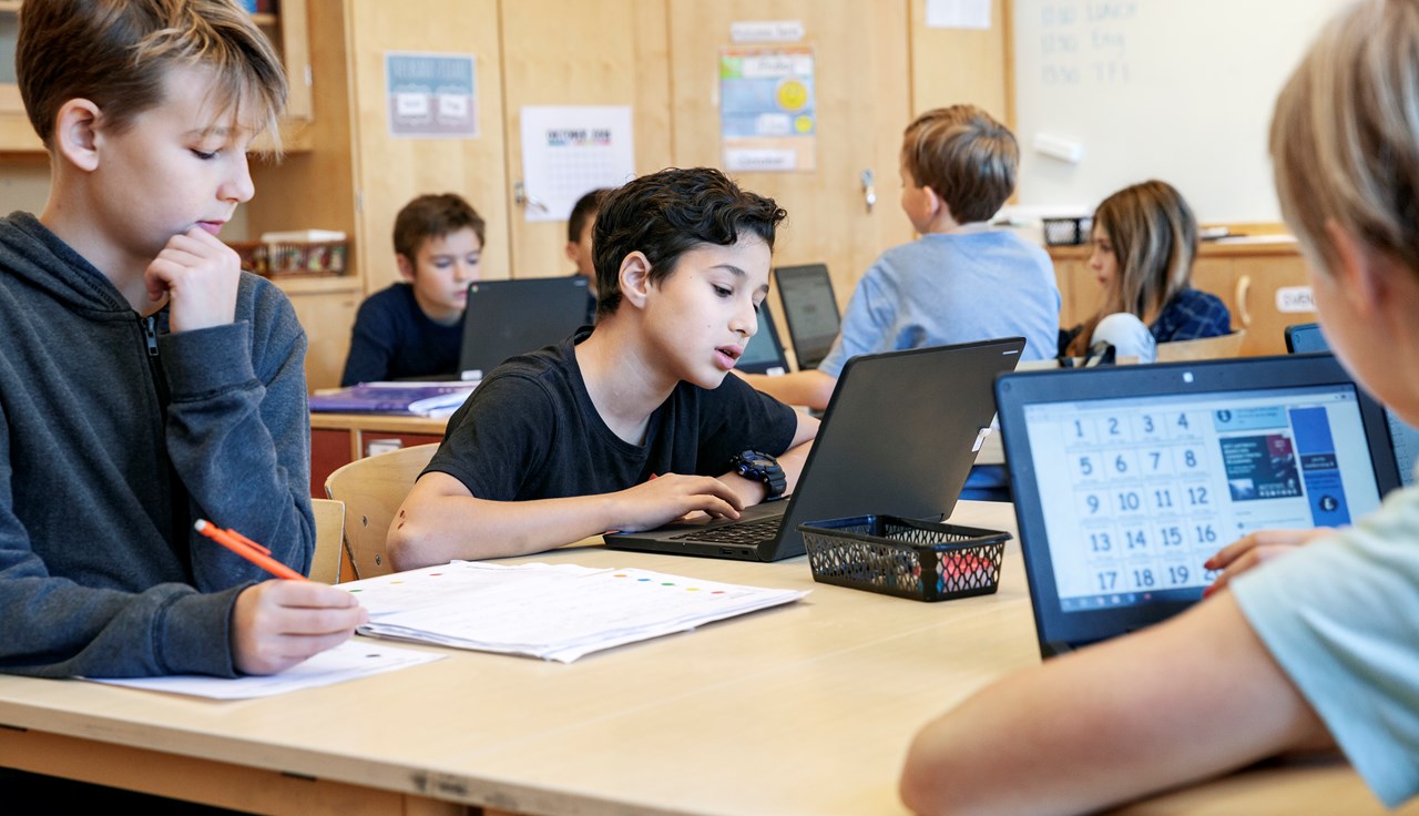 Barn i klassrum jobbar med bärbara datorer.