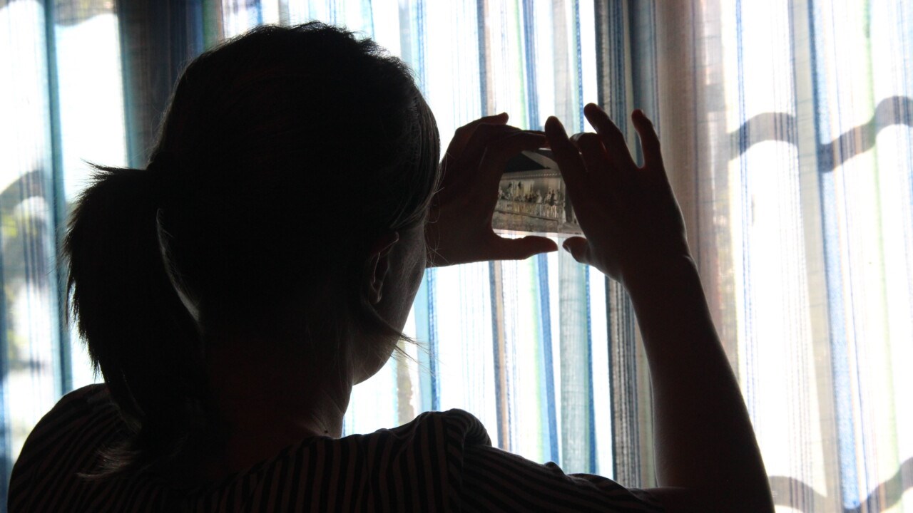 Jenny Ingridsdotter ute hos informant fotograferar ut ur ett fönster och bilden är tagen i motljus.