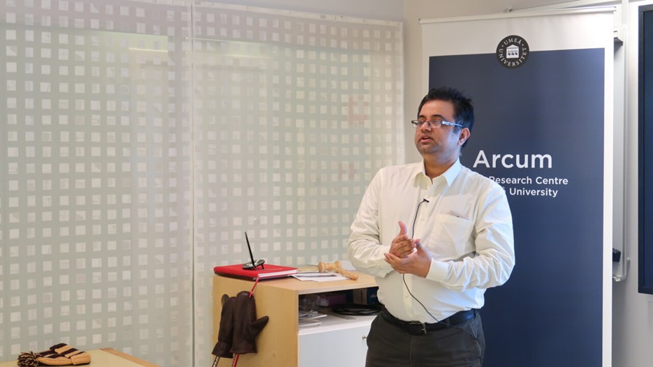 Krishna Kumar speaks in front of a powerpoint presentation.