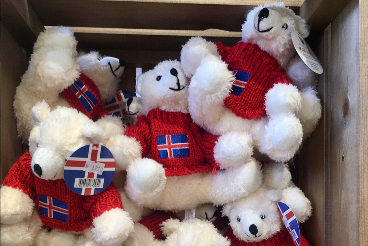 White teddy bears in a wooden box with Icelandic shirts and a price tag