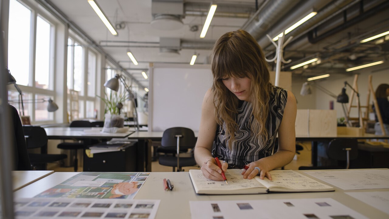 Arkitektstudenten Frida Block sitter vid sin plats och ritar på en ritning