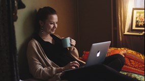 En student sitter hemma på sin säng och pluggar