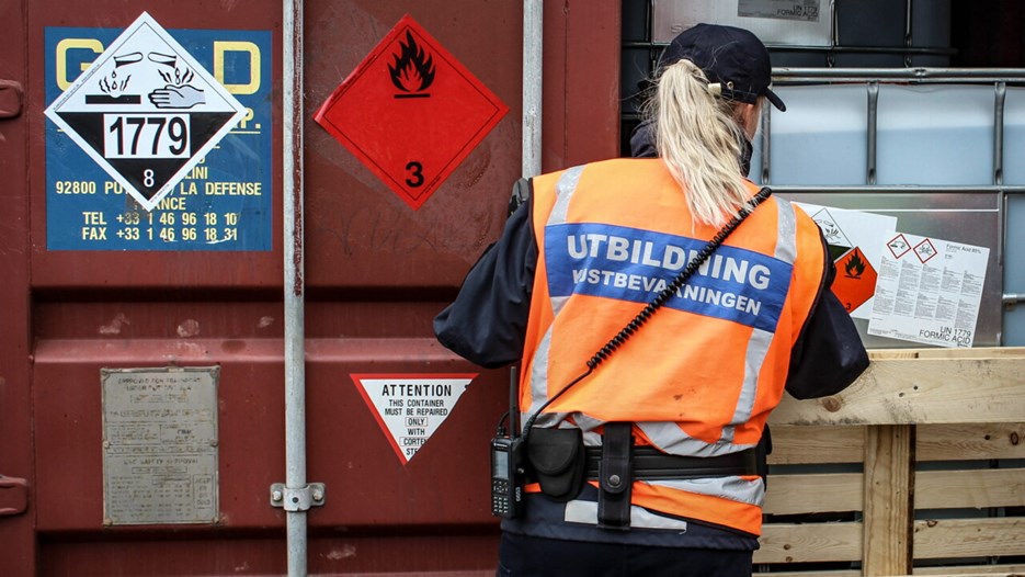 En person med en väst som det står utbildning kustbevakning på står vid en container.
