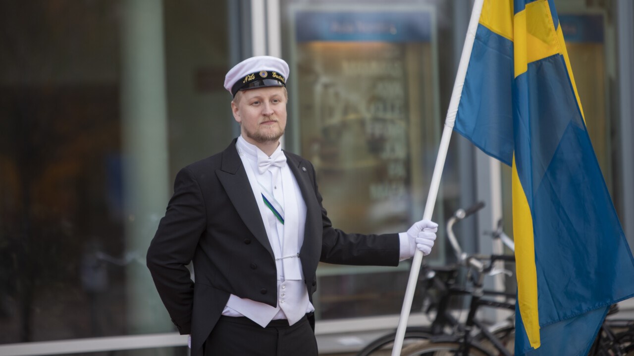 Studentmarskalk håller flaggan vid mottagandet av gäster till Aula Nordica i samband med Årshögtiden 2018.