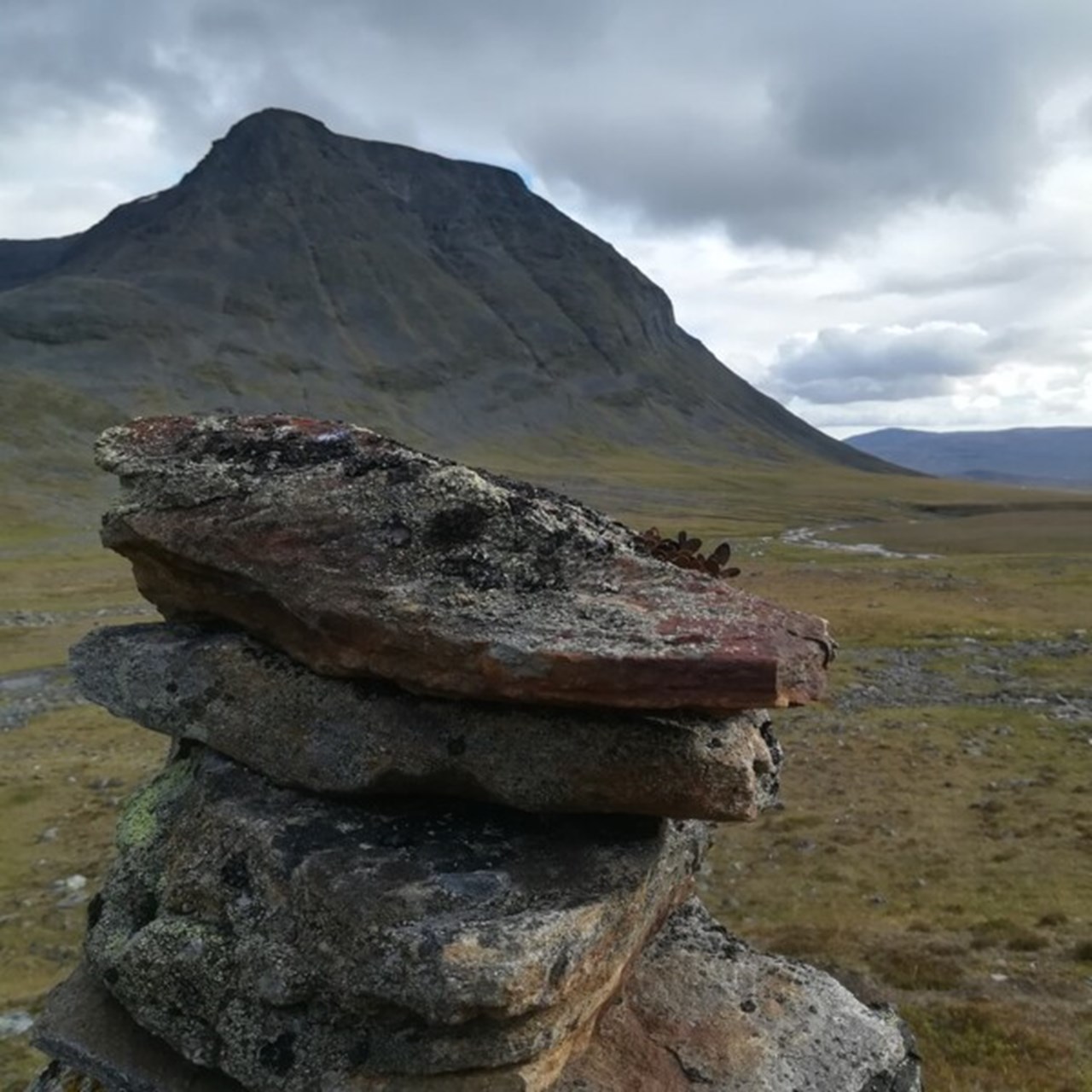 Naturbild från fjällvärlden i Lappland med stenhög i förgrunden.