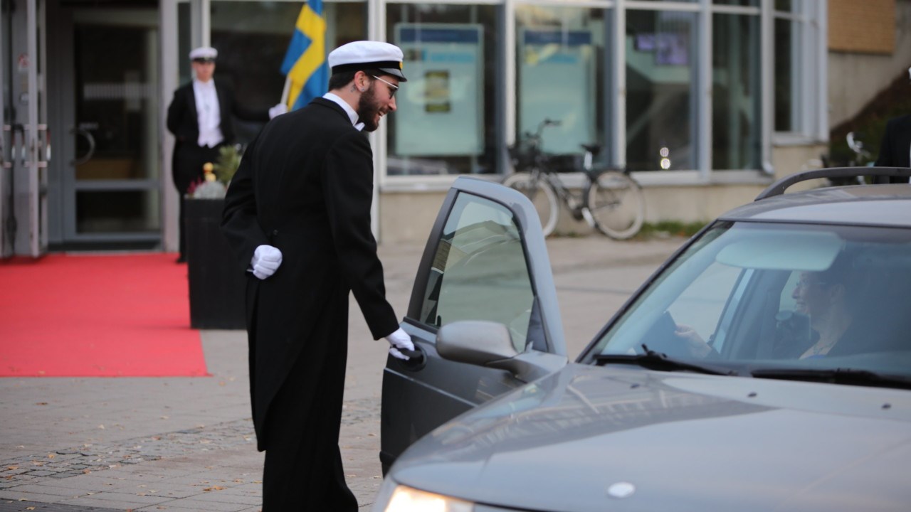 Studentmarskalkar öppnar bildörr vid Årshögtiden.
