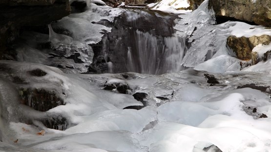 Bäck i snölandskap med stenar och is och vatten som forsar