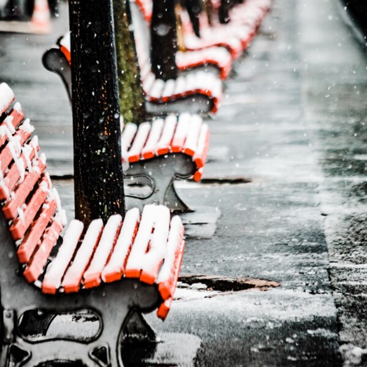 A long one with red wooden benches covered with snow on an icy street.