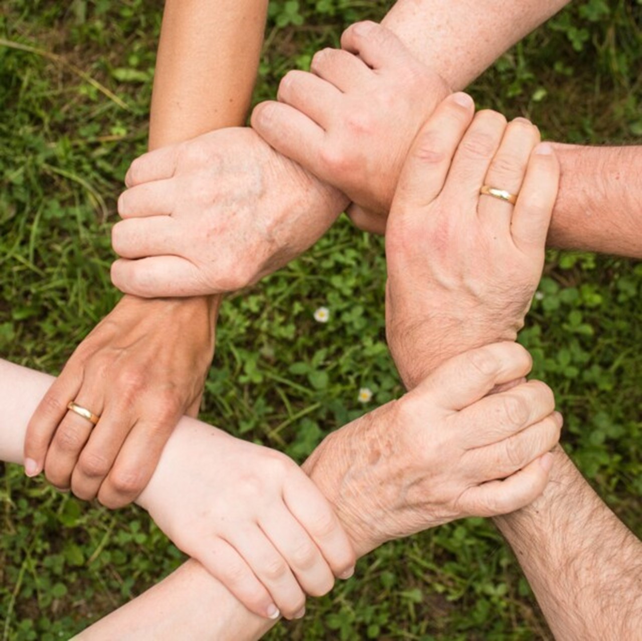 Different generations who keep their hands in the ring so only the hands are visible and tie them together