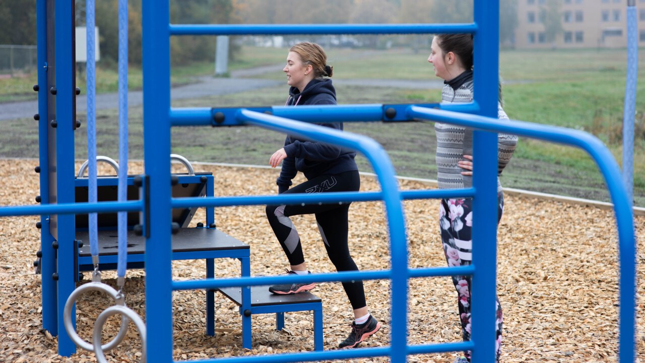 ung tjej som tränar på blå träningsmaskin utomhus