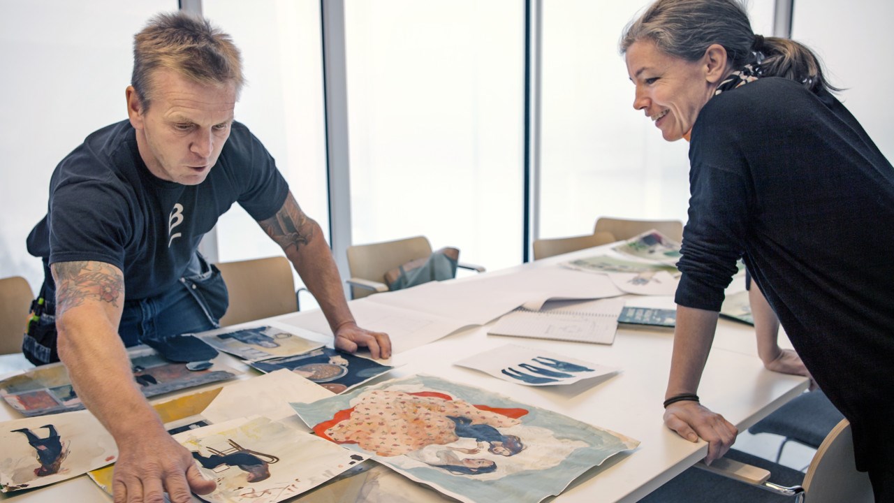 Museitekniker Olle Ebgen Ljungblad grupperar Sara Lundbergs målningar på Bildmuseet i Umeå.