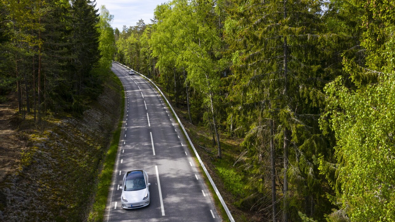 Bild på bil som kör på väg genom skogen