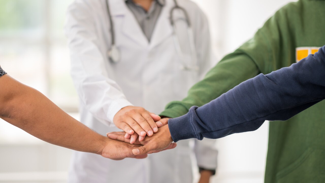 Samarbete, grupp med händer på varandra varav en läkares hand.
