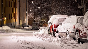 Vinterväglag med insnöade, parkerade bilar.