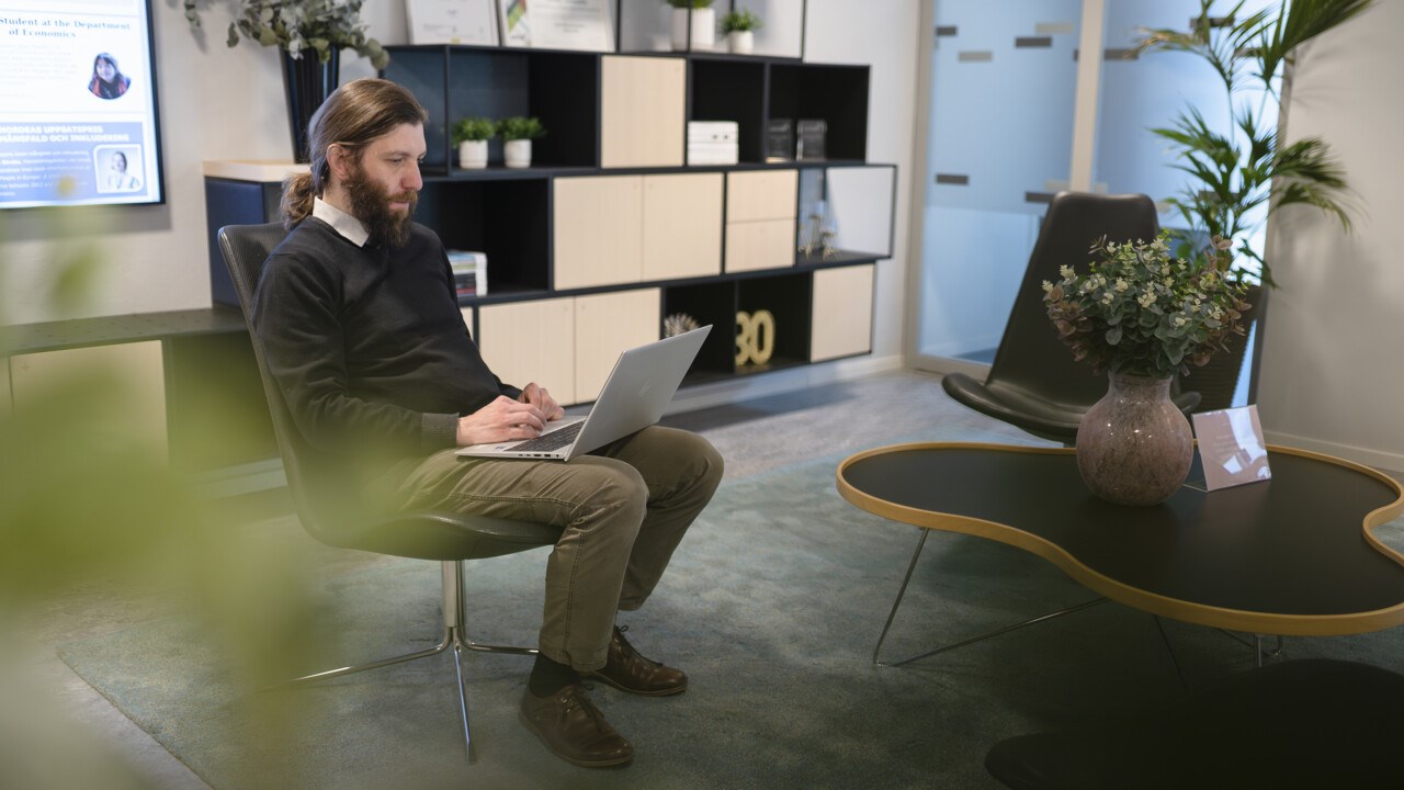 Norbert Steigenberger sitter i en stol och arbetar med sin dator. 