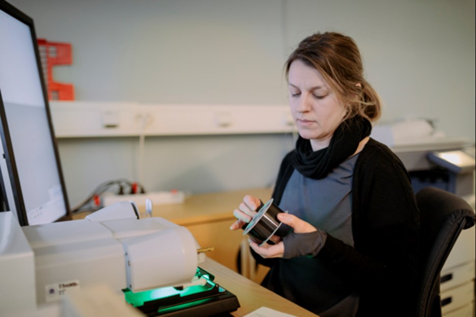 Researcher sitting in front of a computer with a roll of film