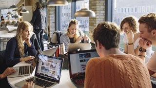 Studenter med bärabara datorer samarbetarvid ett runt bord