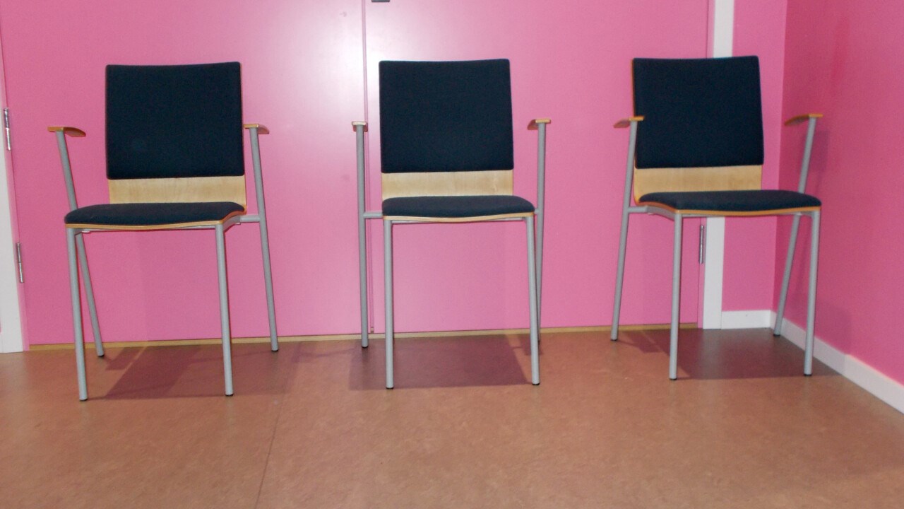 Tre stolar står på rad, mot en rosa vägg.