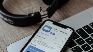 Dator, hörlurar och mobil med zoom-app.