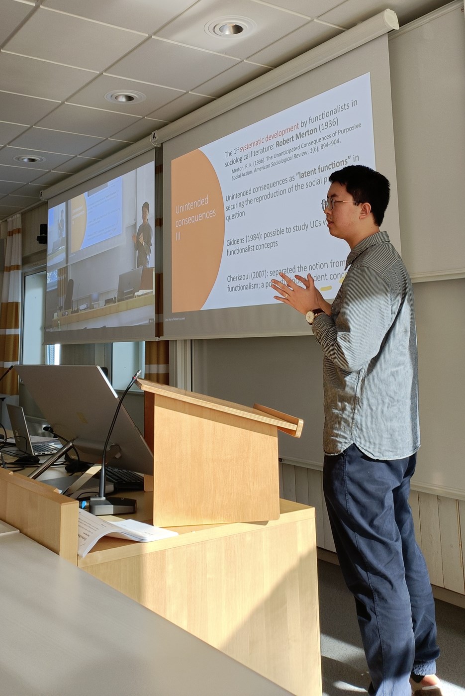 Yue Wang stands in front of a powerpoint