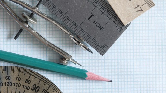 Uppsättning med rit- och mätinstrument och penna på rutat papper.
