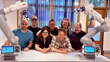 Gruppen Collaborative Robotics Lab som poserar med två robotarmar från ABB