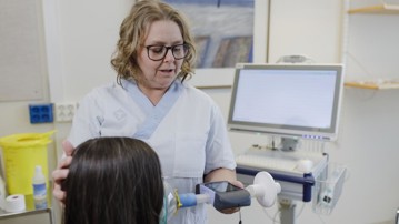 Forskningssjuksköterskan och studiekoordinatorn Nina Sundqvist mäter lungfunktionskapaciteten med hjälp av en spirometer.