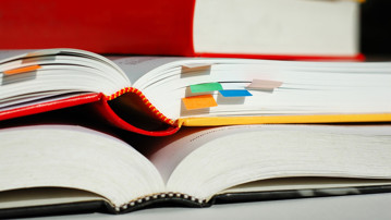 Books are piled with bookmarks. Genrebild från Mostphotos.