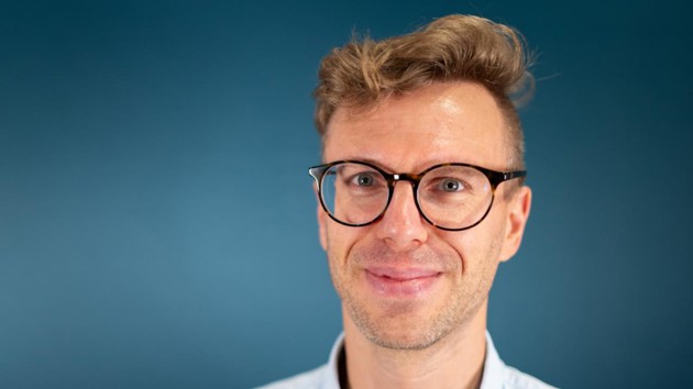 A man wearing glasses and a blue shirt.