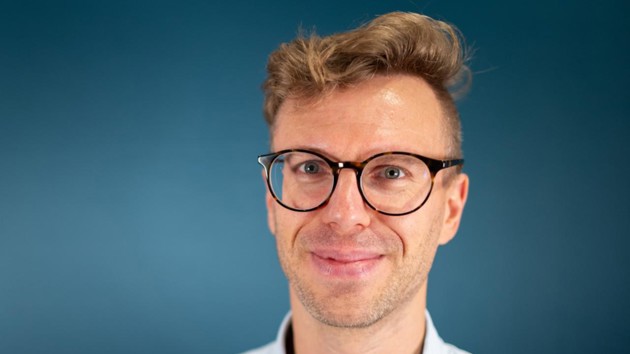 A man wearing glasses and a blue shirt.