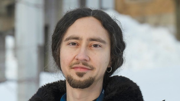 A man standing in front of a building wearing a black jacket.