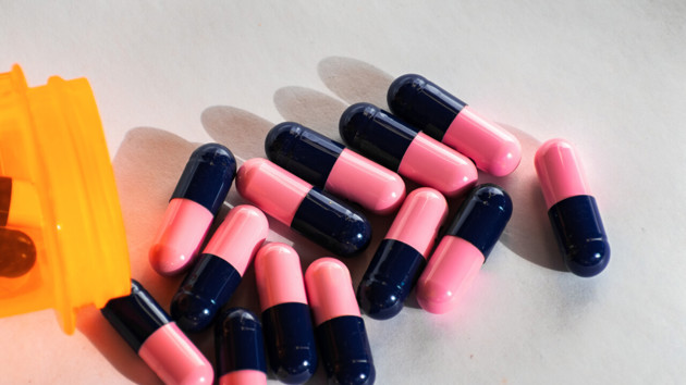 Närbild på rosa och blå antibiotikatabletter.