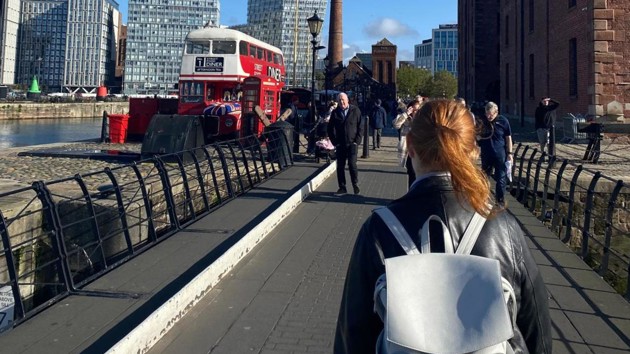 En kvinna med ryggsäck går över en bro.