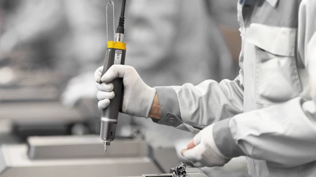 A person in a factory holding a machine.
