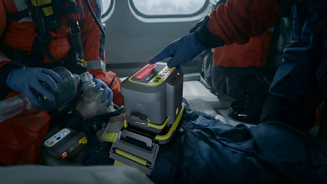 A man in a red and blue uniform is holding a tool.