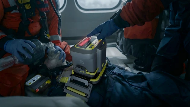 A man in a red and blue uniform is holding a tool.