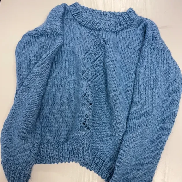 En blå tröja ligger på en vit yta.