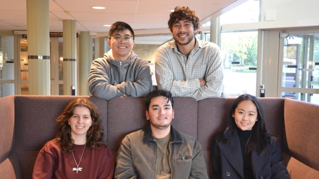 Image of five international students on and around a sofa