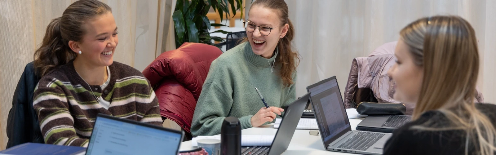 En grupp studenter sitter vid ett bord med bärbara datorer.